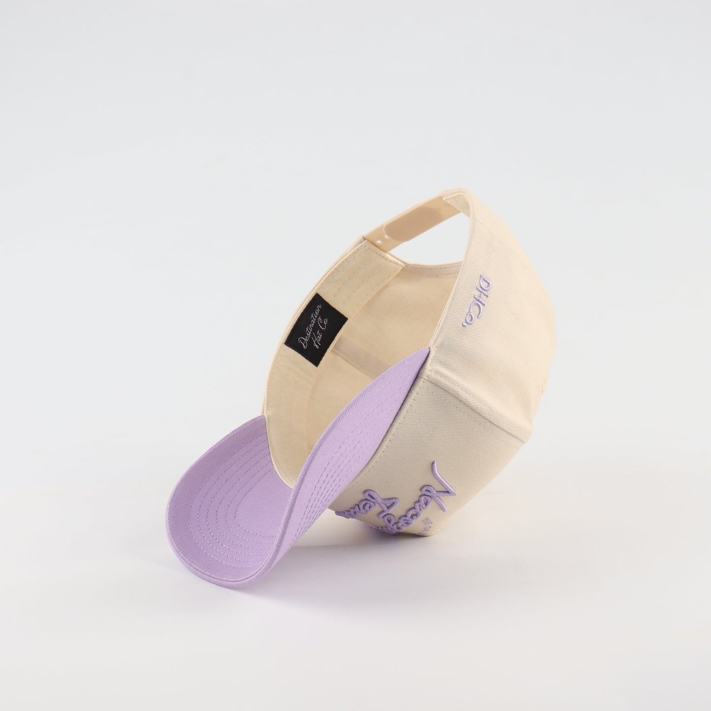 Nacogdoches Script Beige and Purple Pre-curved Trucker Hat
